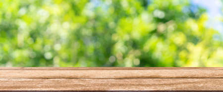Wooden table top on blur green nature background with bokeh.