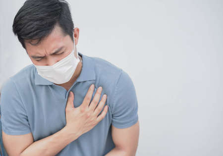 close up asian man wear face mask coughing and touching on chest to check lung while breathing in...