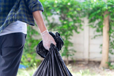 close up man hand holding trash bag to go to throwing in the bin at outdoor park for world entertainment day and save ecology conceptの写真素材