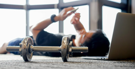close up dumbbell with young man in sit-up pattern on the floor to workout with online trainer course from website for quarantine lifestyle and healthy conceptの写真素材