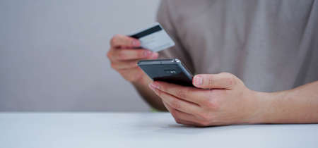 close up adult man touching on smartphone in quarantine time to choose or select items on marketplace website and paying order by using credit card for modern and comfortable lifestyle conceptの写真素材