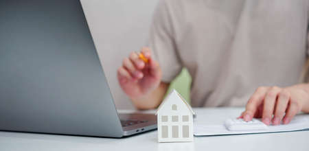 close up young man hand press on calculator to check and summary expense of home loan mortgage for refinance plan , people lifestyle conceptの写真素材