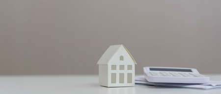 Real estate and property investment concept. House model and calculator on white table.の写真素材
