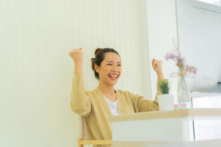close up young employee woman raising hand with happiness after completed challenge while video conferences with team for work from home and business conceptの写真素材