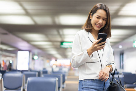 close up businesswoman holding smartphone to checking list of task while standing to waiting boarding time from airline for business and travel conceptの写真素材