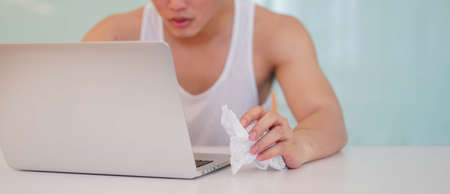 close up young man in pajamas using laptop to looking  movie from website alone in bedroom for...