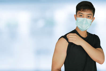 pack of young asian man with protective face mask sand showing bandage on shoulder to expression after antibody vaccinated isolated on blur hospital background for health conceptの写真素材