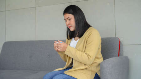 close up shot of adult asian woman sitting on sofa and holding pregnancy kit test and waiting result...