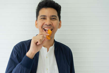 close up focus asian man hand hold and showing fried chicken meal for eat at office for fast food concept and healthcare livingの写真素材