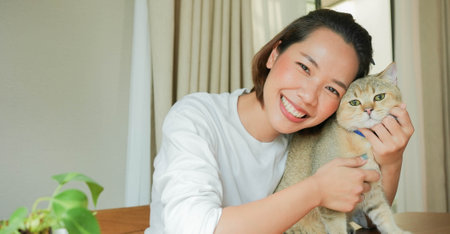 close up beautiful asian woman smile with charming adorable cat in living room for cat lover and lifestyle people conceptの写真素材