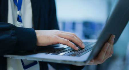 close up network engineering man hand typing keyboard laptop to configure command software and check connectivity on network broadband at data center operation room for technology conceptの写真素材