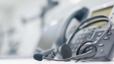 close up soft focus on headset with telephone devices at office desk for customer service support conceptの写真素材
