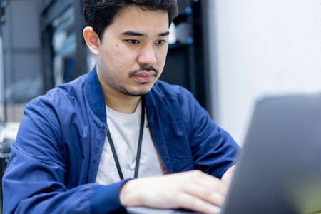 close up network engineering man typing keyboard laptop to configure command software and check connectivity on network broadband at data center operation room for technology conceptの写真素材