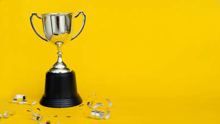 close up trophy championship cup with ribbon and confetti on yellow background for award winner of sport conceptの写真素材