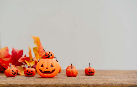 close up top view group of orange spooky pumpkins and maple leaves lay on brown retro wood tabletop...