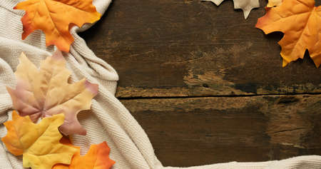 close up top view on brown wood texture with maple leaves on ripple fabric background texture for autumn season collection design conceptの写真素材