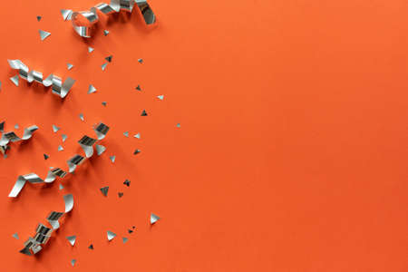 close up on group of silver color of rolling ribbon and confetti on panoramic orange background with copy space for happy new year ,festival ,birthday and anniversary, concept designの写真素材