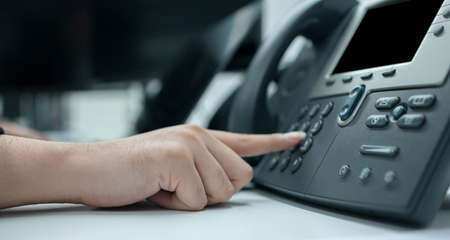 Close-up view of businessman's hand pressing button on telephoneの写真素材