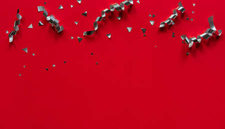 close up on group of silver color of rolling ribbon and confetti on red background with copy space for merry christmas, happy new year ,festival ,birthday and anniversary, concept designの写真素材