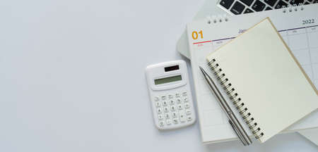 close up top view on calculator with notebook ,calendar and laptop (office supplies) on white color background with copy space for financial business and accounting conceptの写真素材