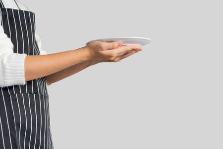 close up woman hand hold empty dish (add your content on image) isolated on gray background for serving menu and order of food conceptの写真素材