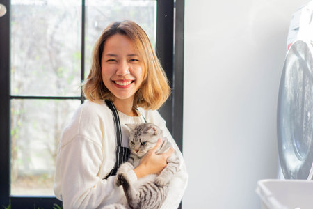 close up beautiful asian woman smile with charming adorable cat in living room for cat lover and lifestyle people conceptの写真素材