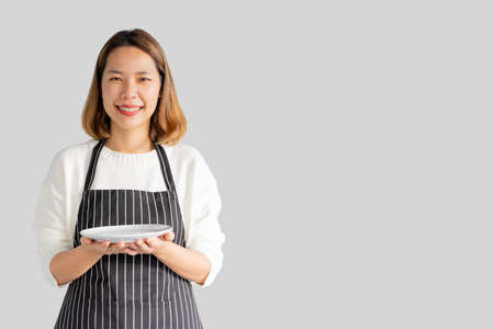 close up young beautiful asian woman hand hold empty dish (add your content on image) isolated on gray background for serving menu and order of food conceptの写真素材