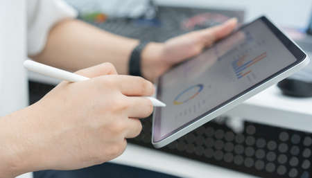 Close-up of businesswoman using digital tablet and analyzing financial data.