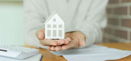 Real estate agent holding house model in hand. Real estate business conceptの写真素材
