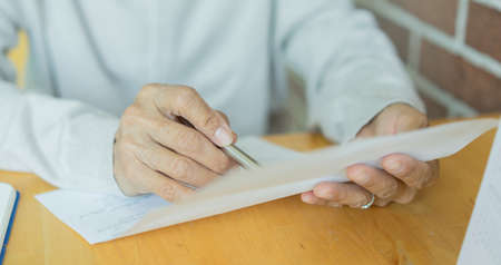 Close-up of a man's hands holding a pen and filling a document.の写真素材