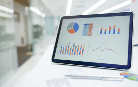 Tablet computer with financial charts on the table in modern office.の写真素材