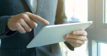 Businessman using digital tablet in office. Close up of male hands using tablet.
