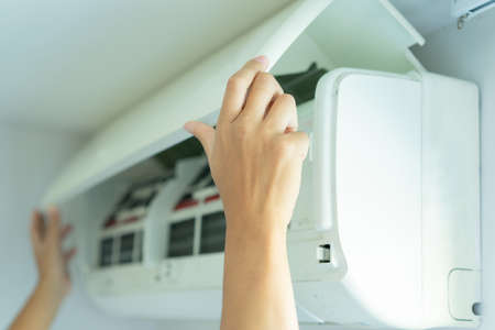 Close-up of woman hands open the air conditioner in the room.の写真素材