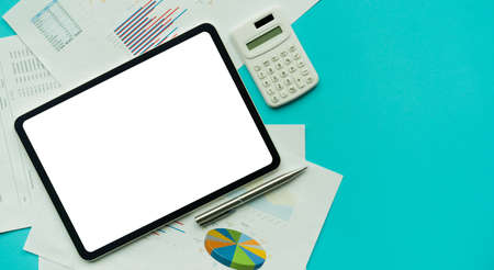 Tablet computer with blank screen and calculator on blue background. Business concept