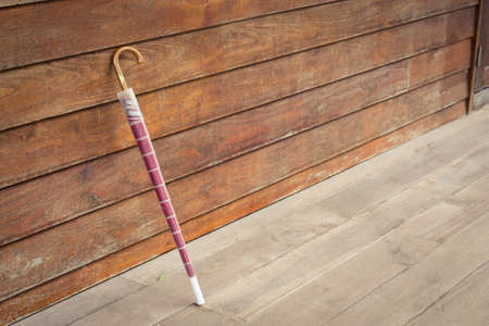 Pink umbrella is leaning on the wooden wall.の写真素材