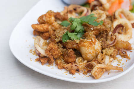 Fried squid with garlic in white dish on the table.の写真素材