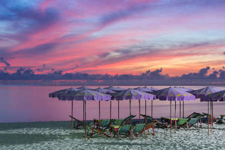 Purple umbrella and green chairs in morning beach, sunrise shot.の写真素材