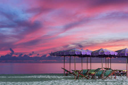 Purple umbrella and green chairs in morning beach, sunrise shot.の写真素材