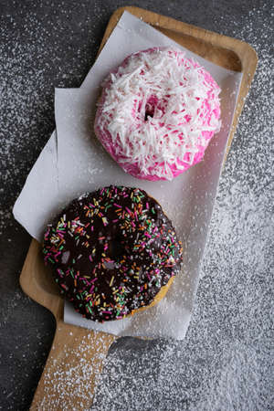 Donut with chocolate glazed and strawberry glazed in wooden tray on concrete table.の写真素材