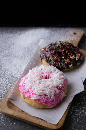 Donut with chocolate glazed and strawberry glazed in wooden tray on concrete table.の写真素材