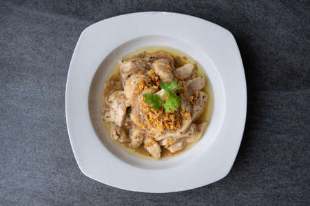Fried chicken with garlic and black pepper in white dish on the concrete table.の写真素材