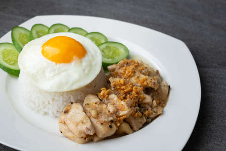 Rice,Fried egg,Fried chicken with garlic and black pepper in white dish on the concrete table.の写真素材