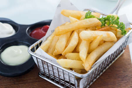 French fries in stainless basket on glass table.の写真素材