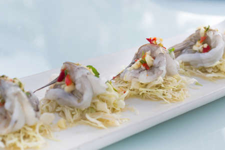 Shrimp in fish sauce with cabbage sliced in white dish on glass table.の写真素材