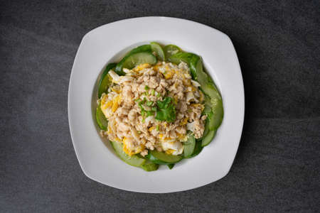 Fried cucumber with chicken egg in white dish on concrete table.の写真素材