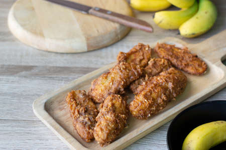 Deep fried banana in wooden dish with banana on table.の写真素材