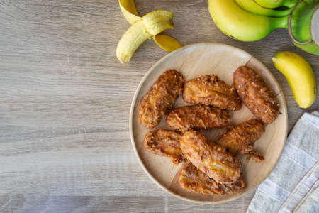 Deep fried banana in wooden dish with banana on table.の写真素材