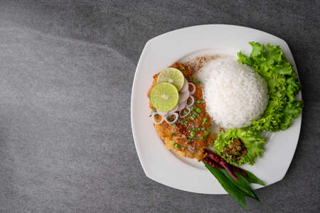 Spicy salad with fried chicken and rice in white dish on table.の写真素材