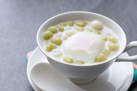 Pandan Thai glutinous rice balls (Bua Loi) in white bowl on table,Boiled egg.の写真素材