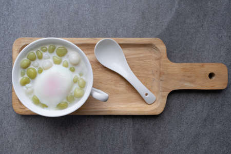 Pandan Thai glutinous rice balls (Bua Loi) in white bowl on table,Boiled egg.の写真素材